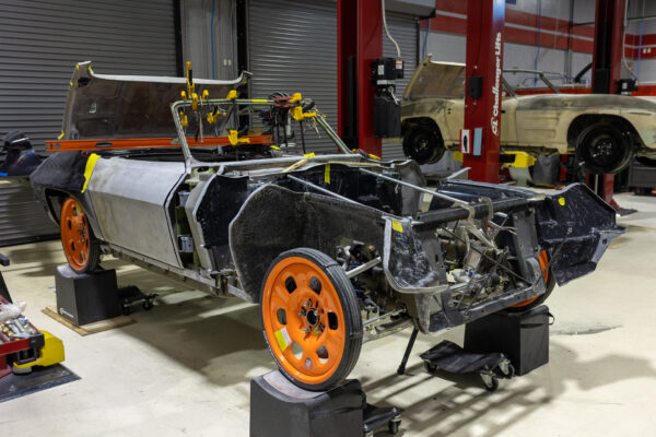 1963 Corvette Sting Ray body shell with roll cage structure and orange wheels during restomod build