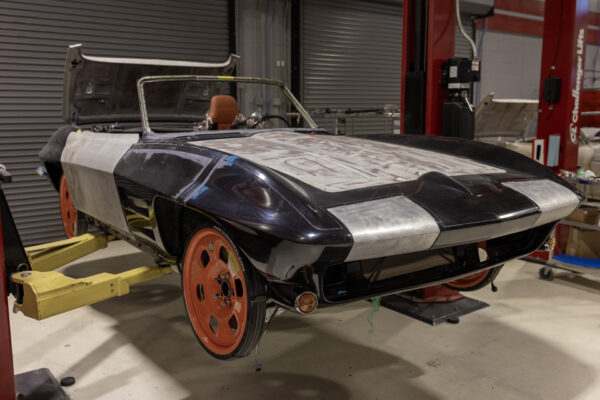 1963 Corvette Sting Ray body masked in black and white tape for paint prep, orange wheels