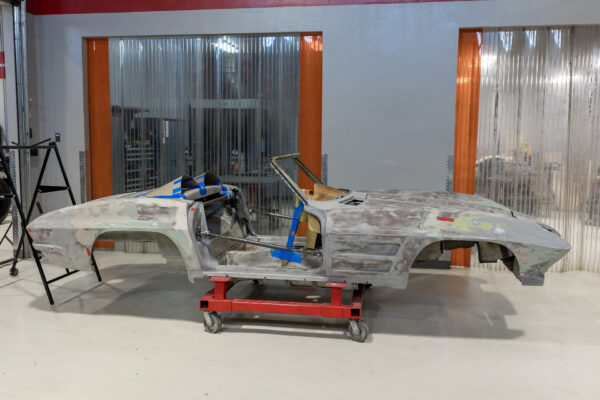 Bare 1963 Corvette Sting Ray shell on a rolling cart in the paint prep area at Crown Customs