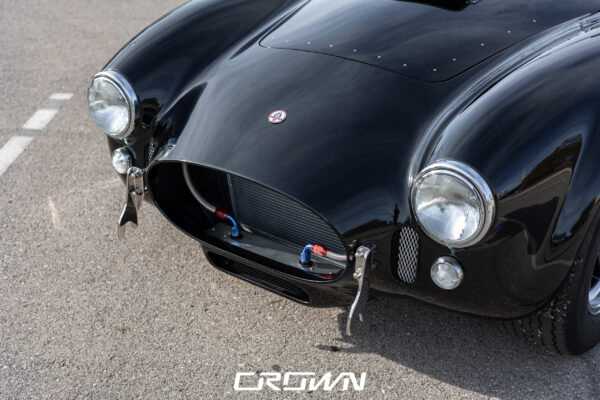 Front three-quarter view of a Superformance MKIII Cobra, chassis SP03627, solid black at Crown Customs in Tucson, Arizona