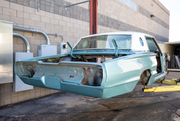 1966 Ford Thunderbird body shell in its original mint paint, hoisted for a full frame-off restoration at Crown Customs