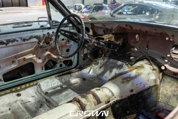 Gutted interior and steering column of a 1966 Ford Thunderbird showing rust damage