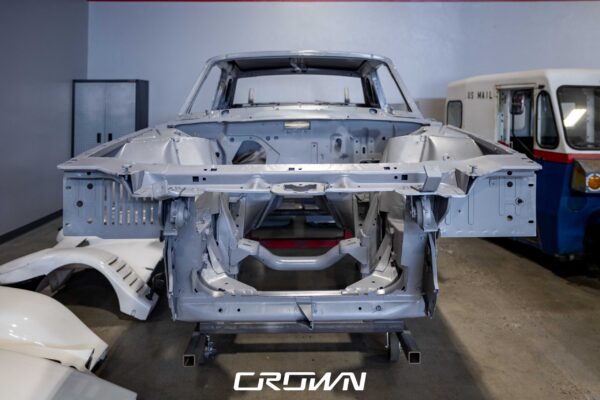 1966 Ford Thunderbird body shell in bare grey primer on a rotisserie after media blasting