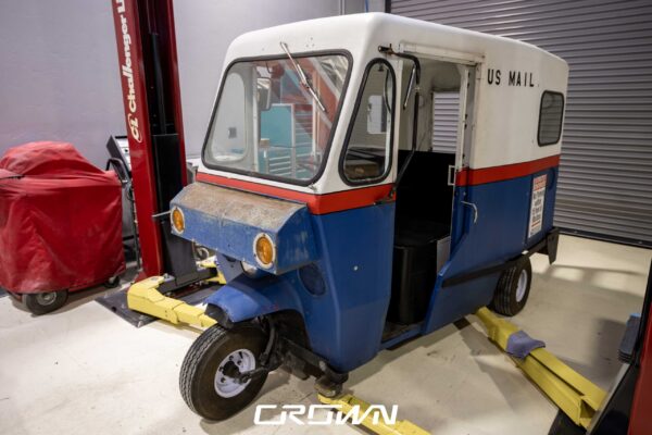 1964 Rand Mailster electric conversion, front three-quarter view on a lift at Crown Customs in Tucson, Arizona
