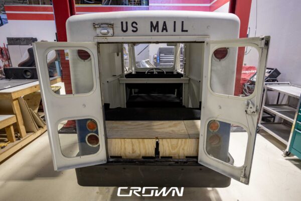 Rear doors of a 1964 Rand Mailster open, revealing a custom plywood battery box mockup for the electric conversion