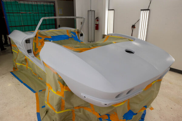1963 Corvette Sting Ray body in the paint booth with candy red base coat being applied
