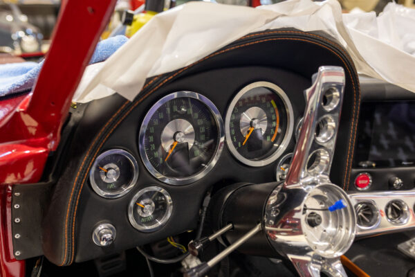 Dashboard gauges and steering wheel of a finished 1963 Corvette Sting Ray in candy red