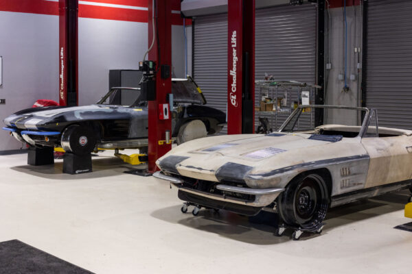 Two Corvette Sting Ray bodies on lifts in the Crown Customs shop during restomod builds