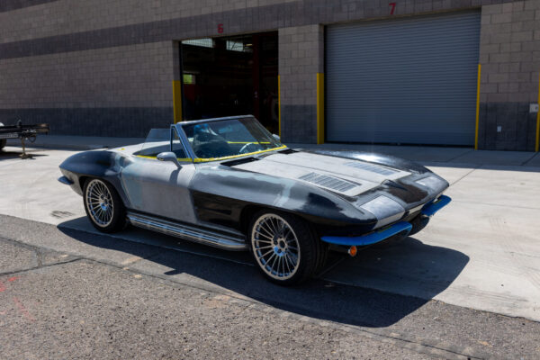 Wide-body 1963 Corvette Sting Ray shell in primer, parked outside Crown Customs in Tucson