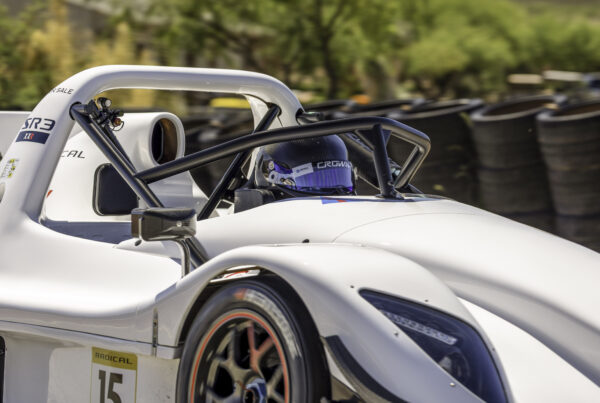 White Radical SR3 with a driver seated in the cockpit beside the tire wall