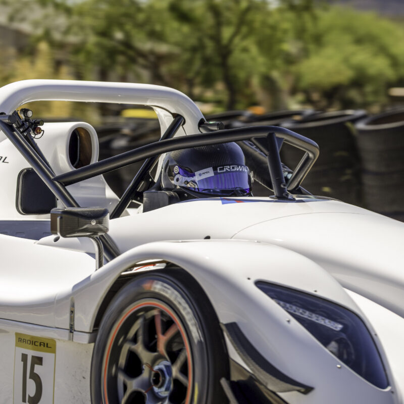 White Radical SR3 with a driver seated in the cockpit beside the tire wall