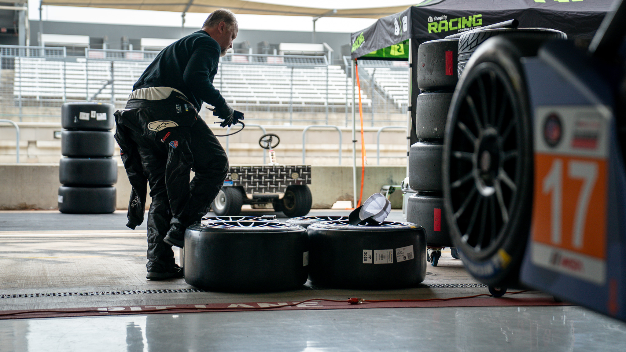 Crown Racing crew member preparing tires beside the No. 17 Ligier JS P320 during IMSA competition at Circuit of The Americas.
