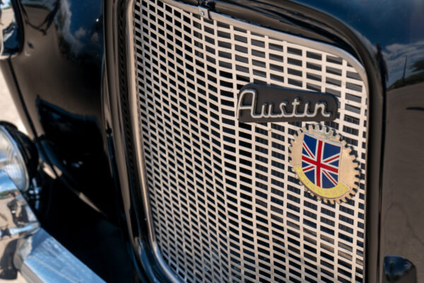 Close view of the Austin script badge and Union Jack shield on the chrome grille of the 1967 Austin FX4 London taxi cab