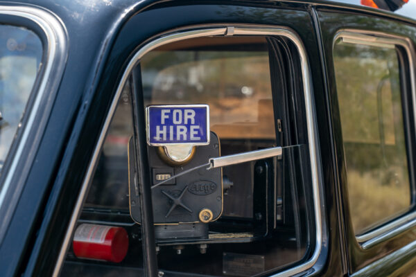 The blue FOR HIRE sign and fare meter seen through the side window of the 1967 Austin FX4 London taxi cab