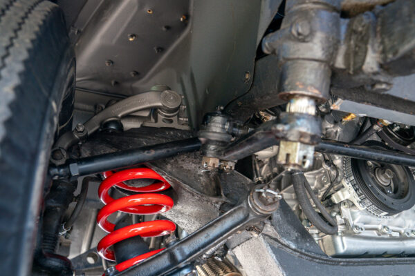 Front suspension of the Austin FX4 London taxi cab with a red coil spring and wishbones, the transmission visible alongside