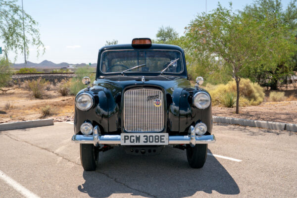 Head on view of the 1967 Austin FX4 London taxi cab showing its upright chrome grille, round headlights and roof mounted taxi lamp