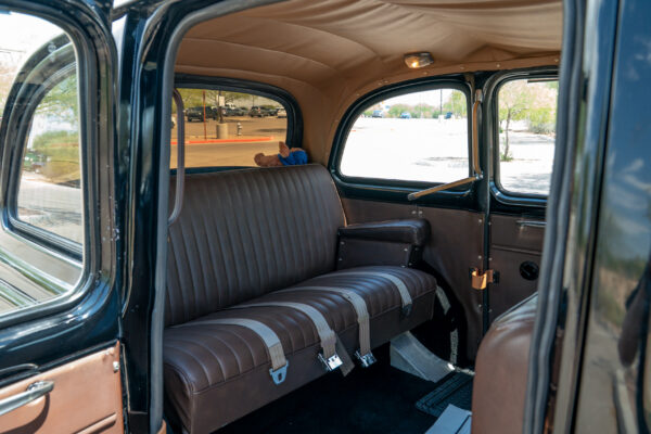 Rear passenger compartment of the Austin FX4 London taxi cab showing the bench seat, wide door opening and pale perforated headliner