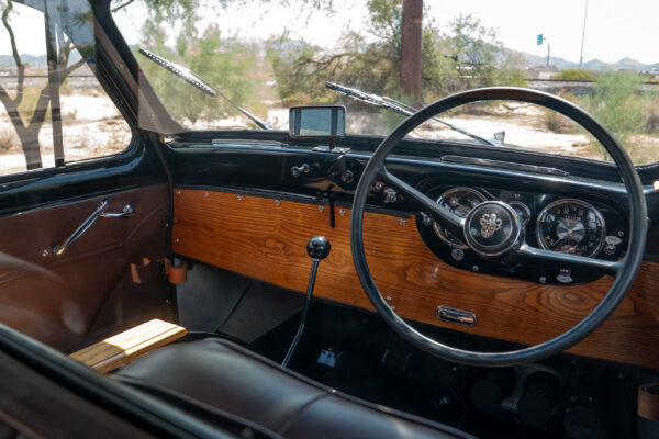 Right hand drive drivers compartment of the 1967 Austin FX4 London taxi cab with a wood dashboard, large steering wheel and original gauges