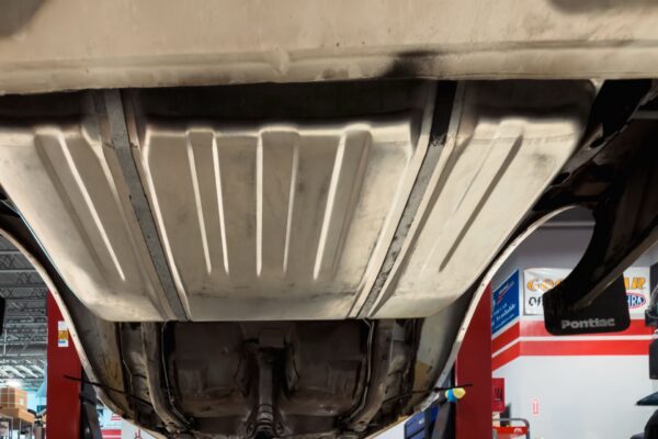 Underbody of the 1978 Pontiac Firebird Formula on the lift at Crown Customs, showing the floor pan and rear axle area during teardown