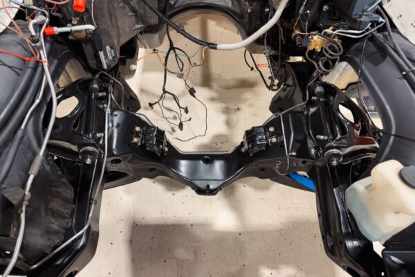 Engine bay of the 1978 Pontiac Firebird Formula with the engine removed, showing the firewall and wiring during teardown