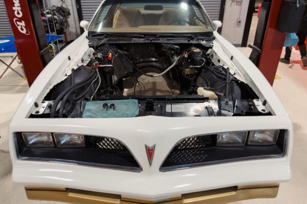 Front end of the white 1978 Pontiac Firebird Formula with the hood raised, showing the twin nostril grille and Pontiac arrowhead badge