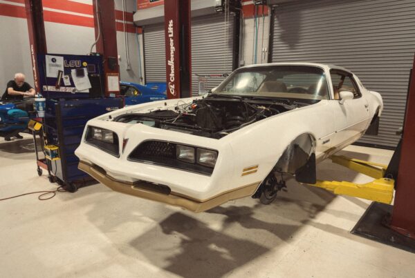 The 1978 Pontiac Firebird Formula on a lift in the Crown Customs shop, finished in a warm period tone that recalls a 1970s Pontiac brochure