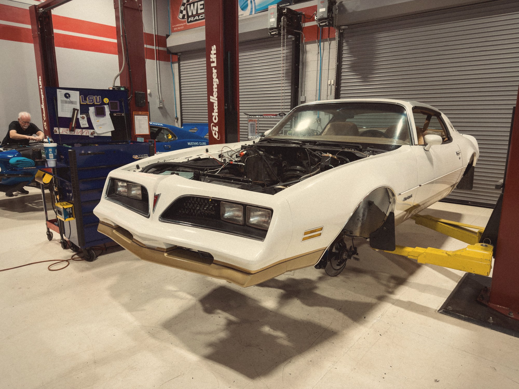 The 1978 Pontiac Firebird Formula on a lift in the Crown Customs shop, finished in a warm period tone that recalls a 1970s Pontiac brochure