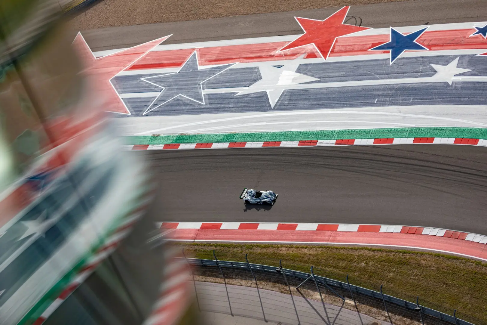 Prototype race car circulating the Circuit of The Americas over the American flag runoff