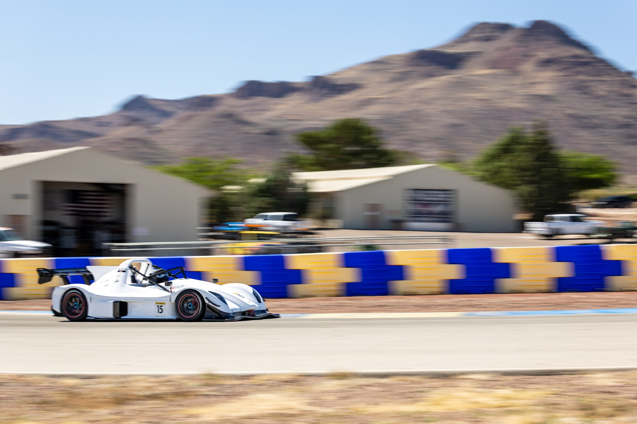 White number 15 Radical SR3 XXR cornering at Inde Motorsports Ranch with the Arizona mountains behind
