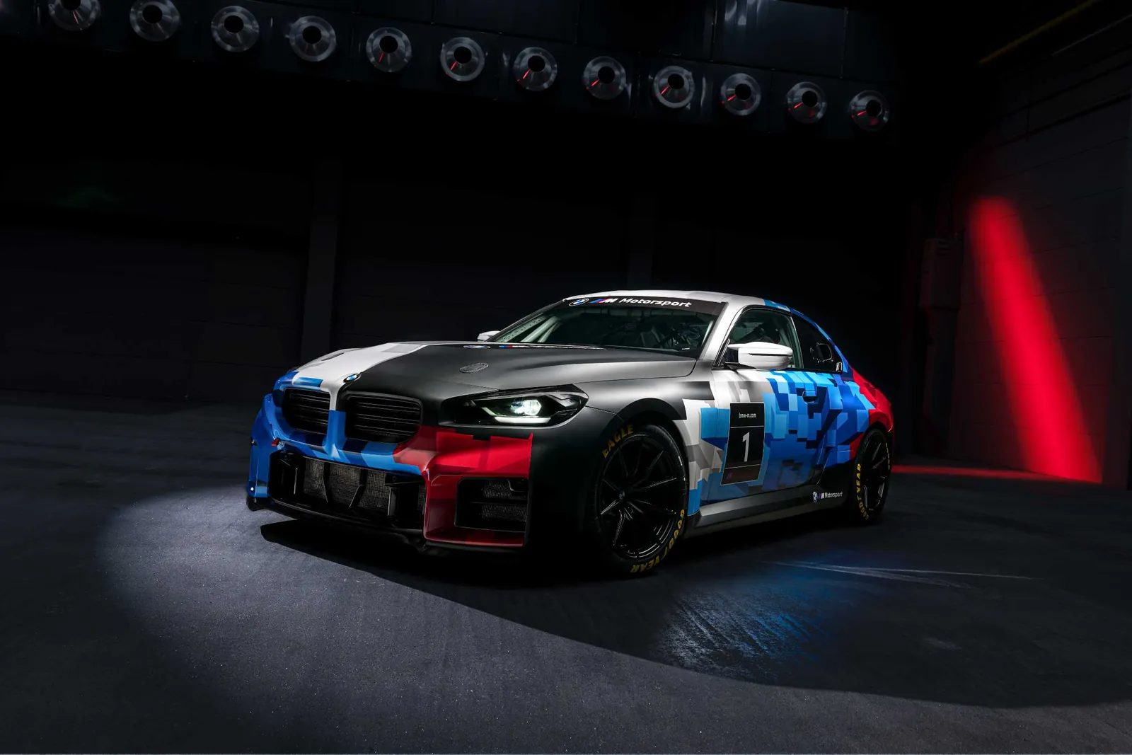 The new BMW M2 Racing customer race car in BMW M Motorsport camouflage livery, lit in a dark studio