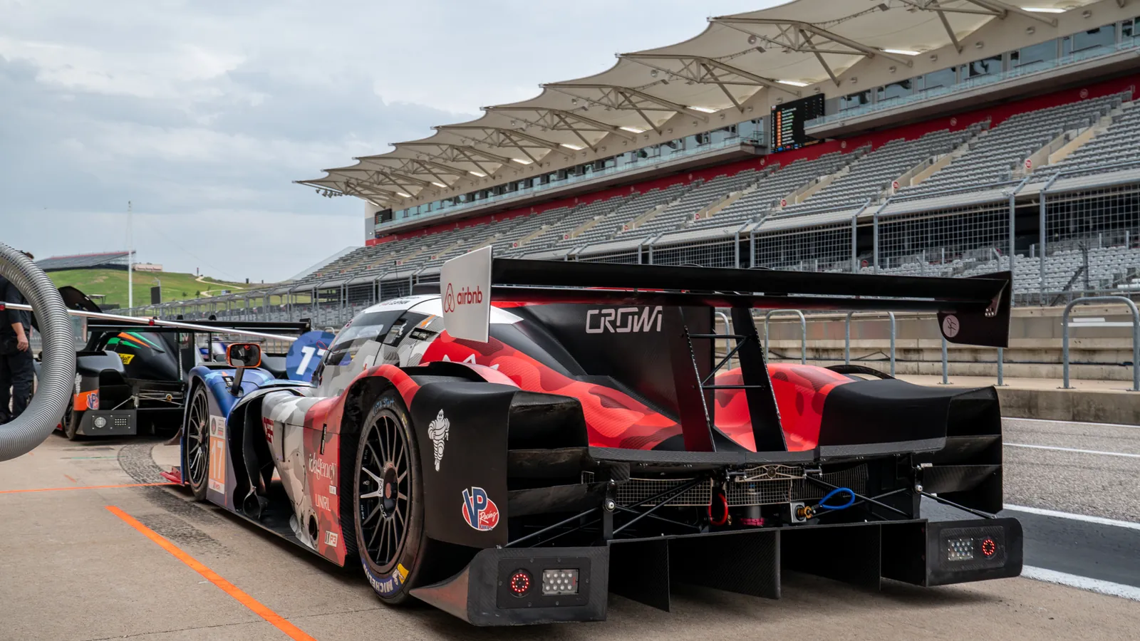 Crown Racing's No. 17 Ligier JS P320 LMP3 prototype in the IMSA pit lane at Circuit of The Americas, the Crown name across its rear wing and the main grandstand behind